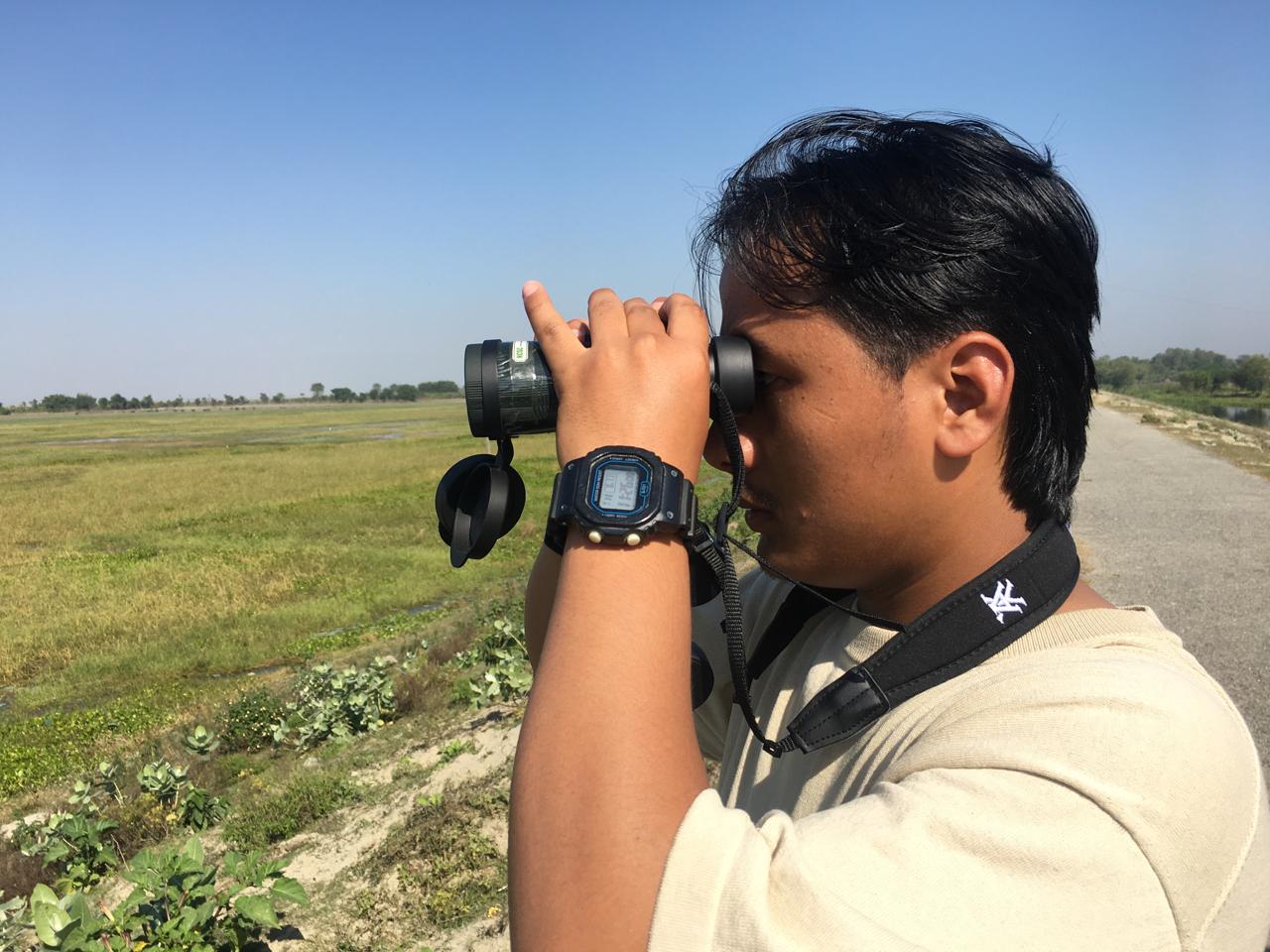 Birdwatcher using binoculars in Nepal forest